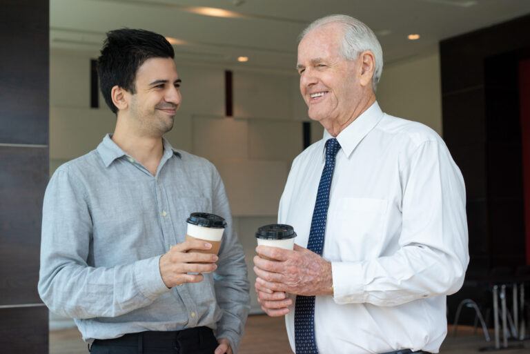 Happy colleagues with take away coffee. Positive smiling businessmen talking and drinking coffee in office. Friendly colleagues concept